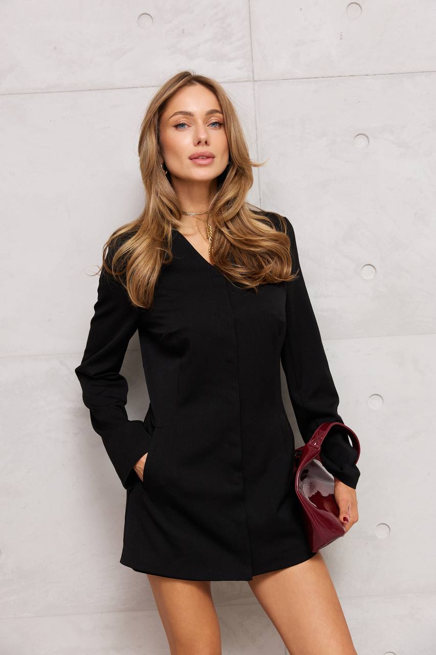 Woman wearing a black dress against a light gray wall