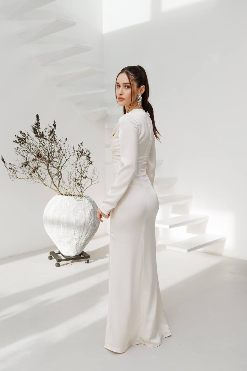 Woman in a white dress holding a white vase with dried plants against a white background