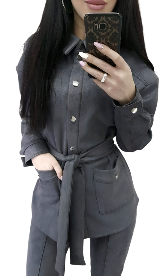 Person wearing a gray outfit with a belt, holding a phone.