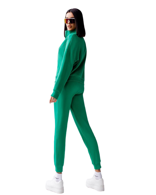 Woman wearing a green tracksuit and white sneakers on a white background
