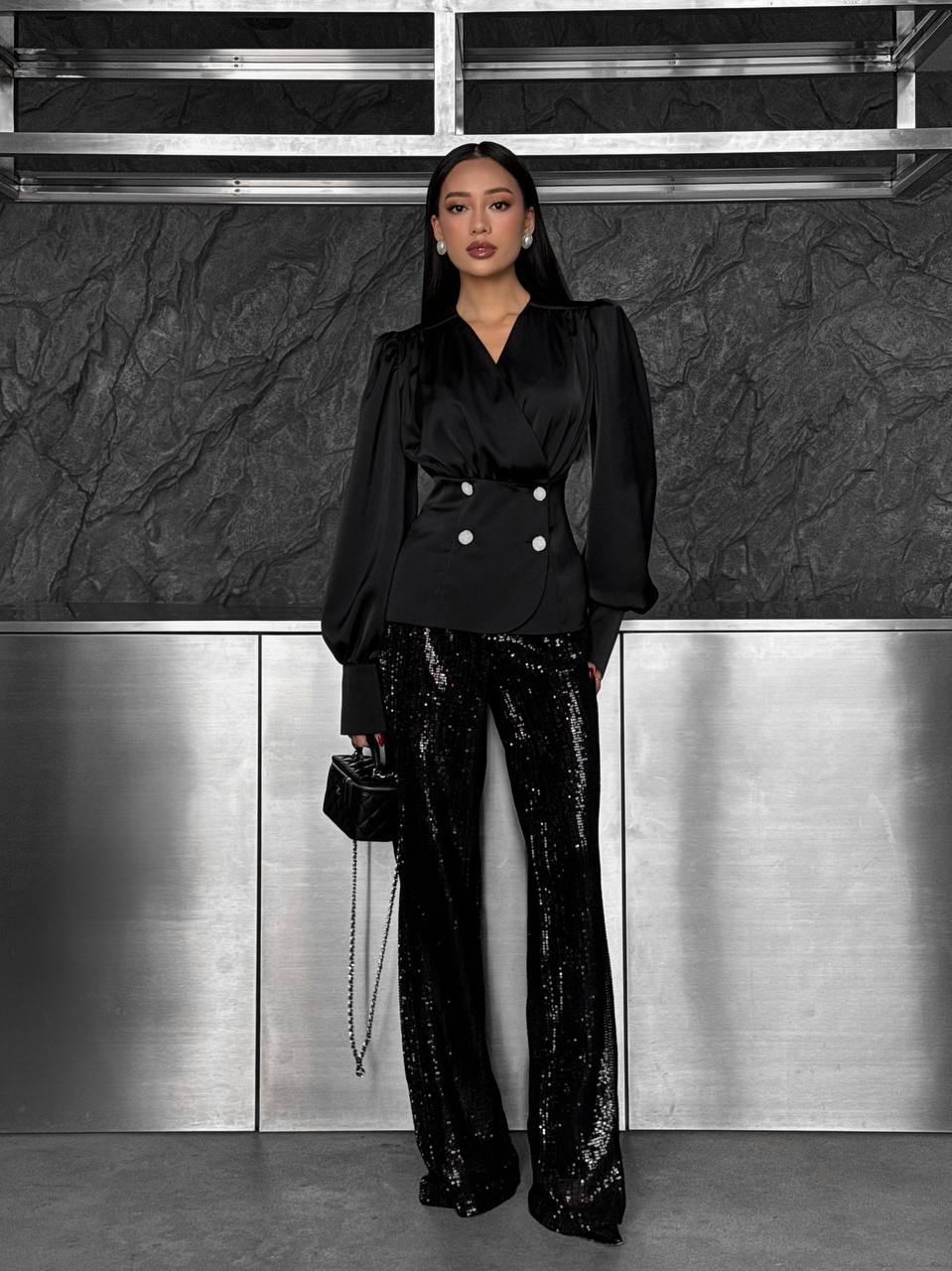 Person wearing a black outfit with sequin pants in an indoor setting