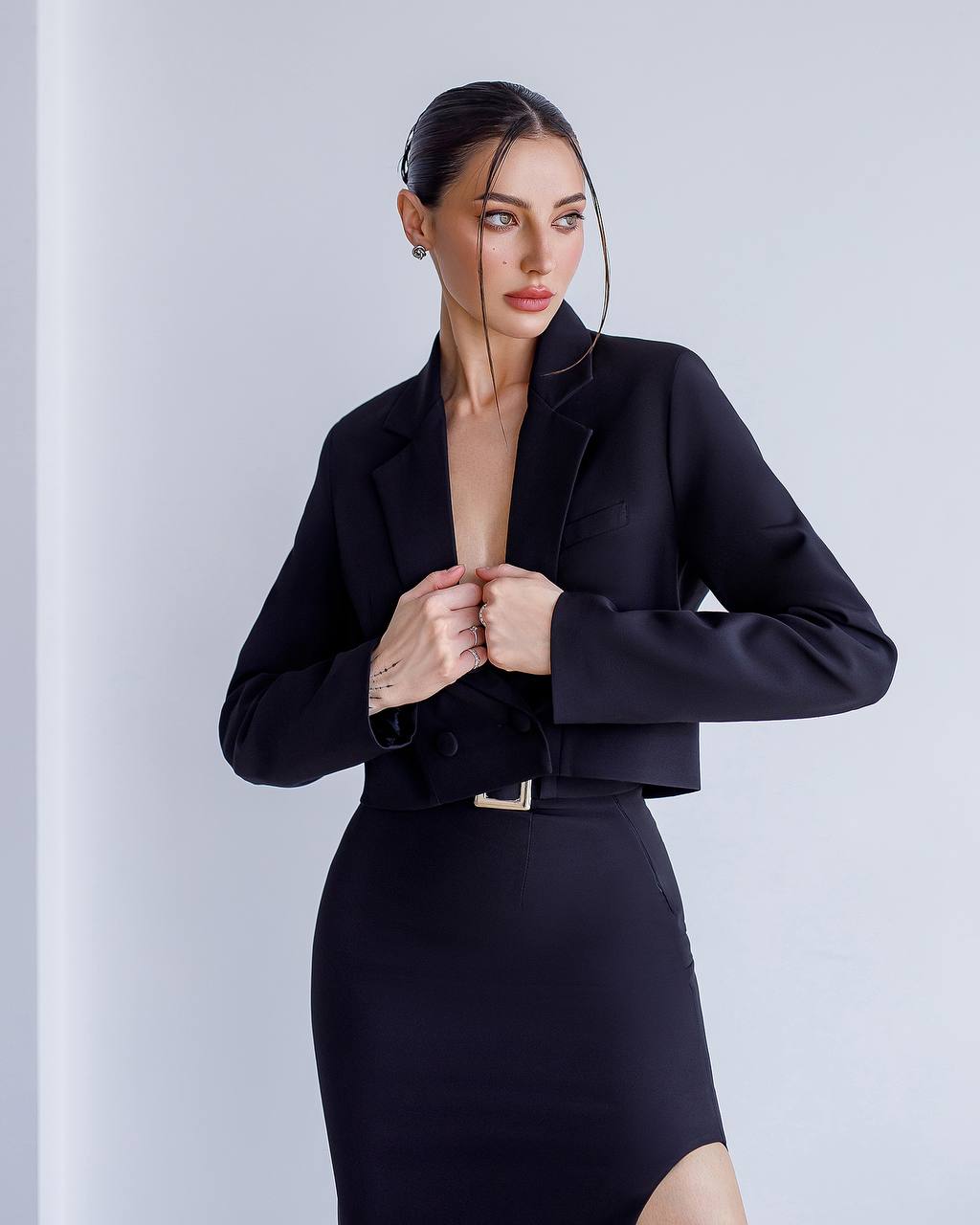 Woman wearing a black outfit against a light gray background