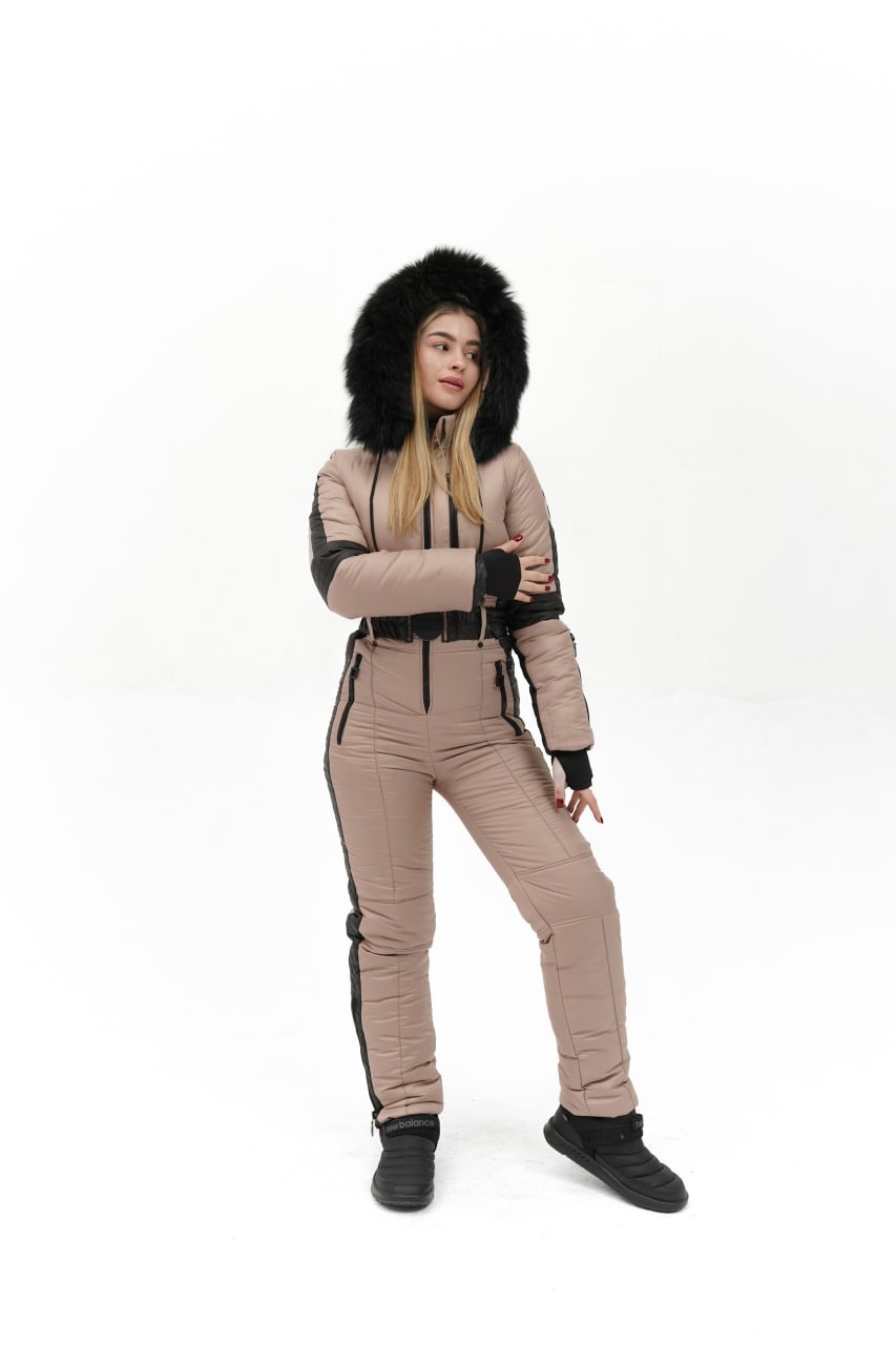 Person wearing a beige snowsuit with black fur hood on a white background