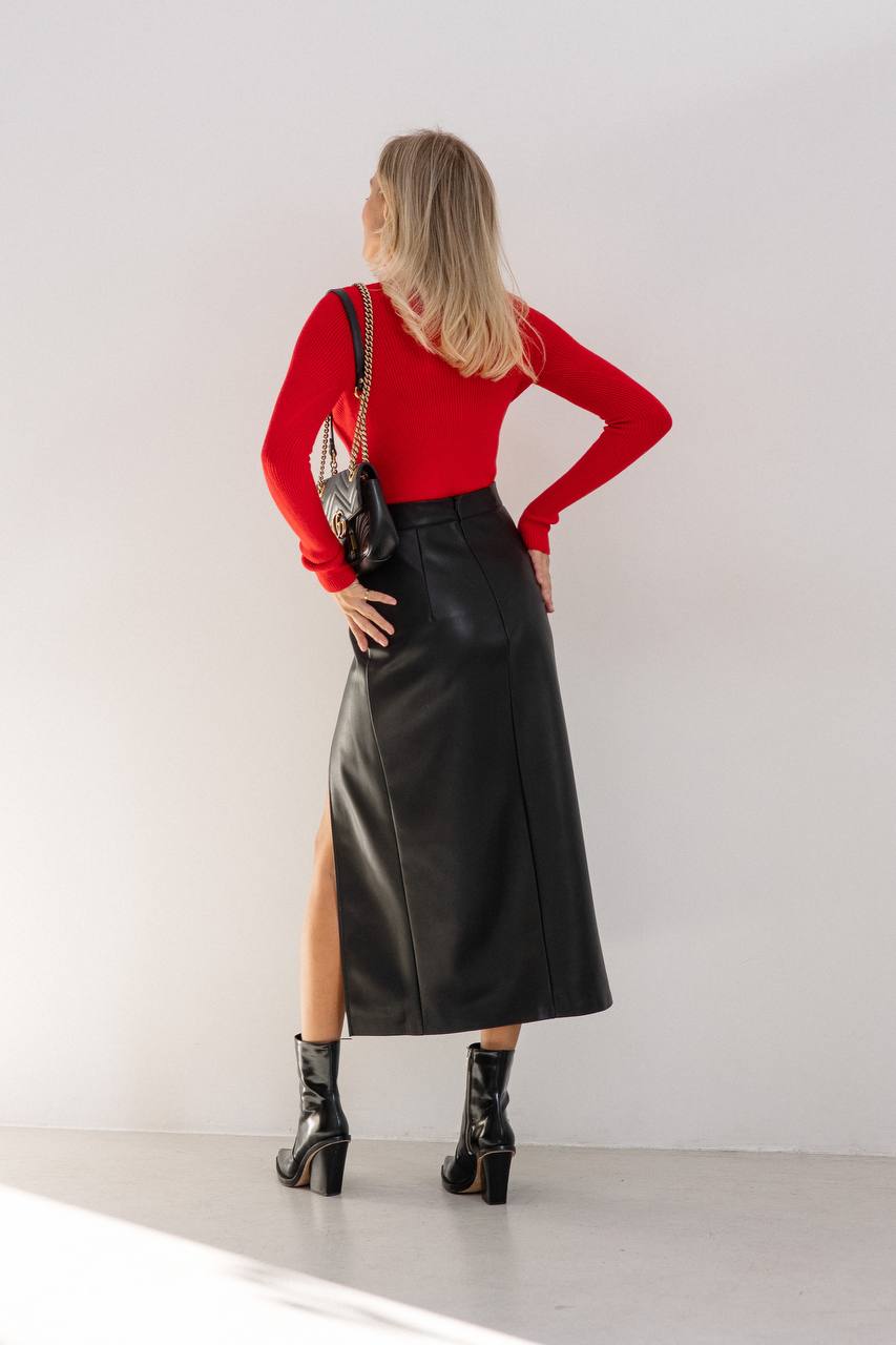 Woman wearing a red top and black leather skirt against a white background