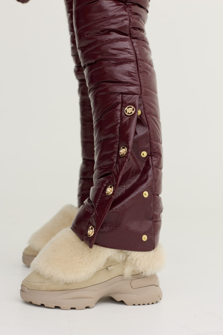 Brown winter boots with gold buttons and white fur lining on a light gray background