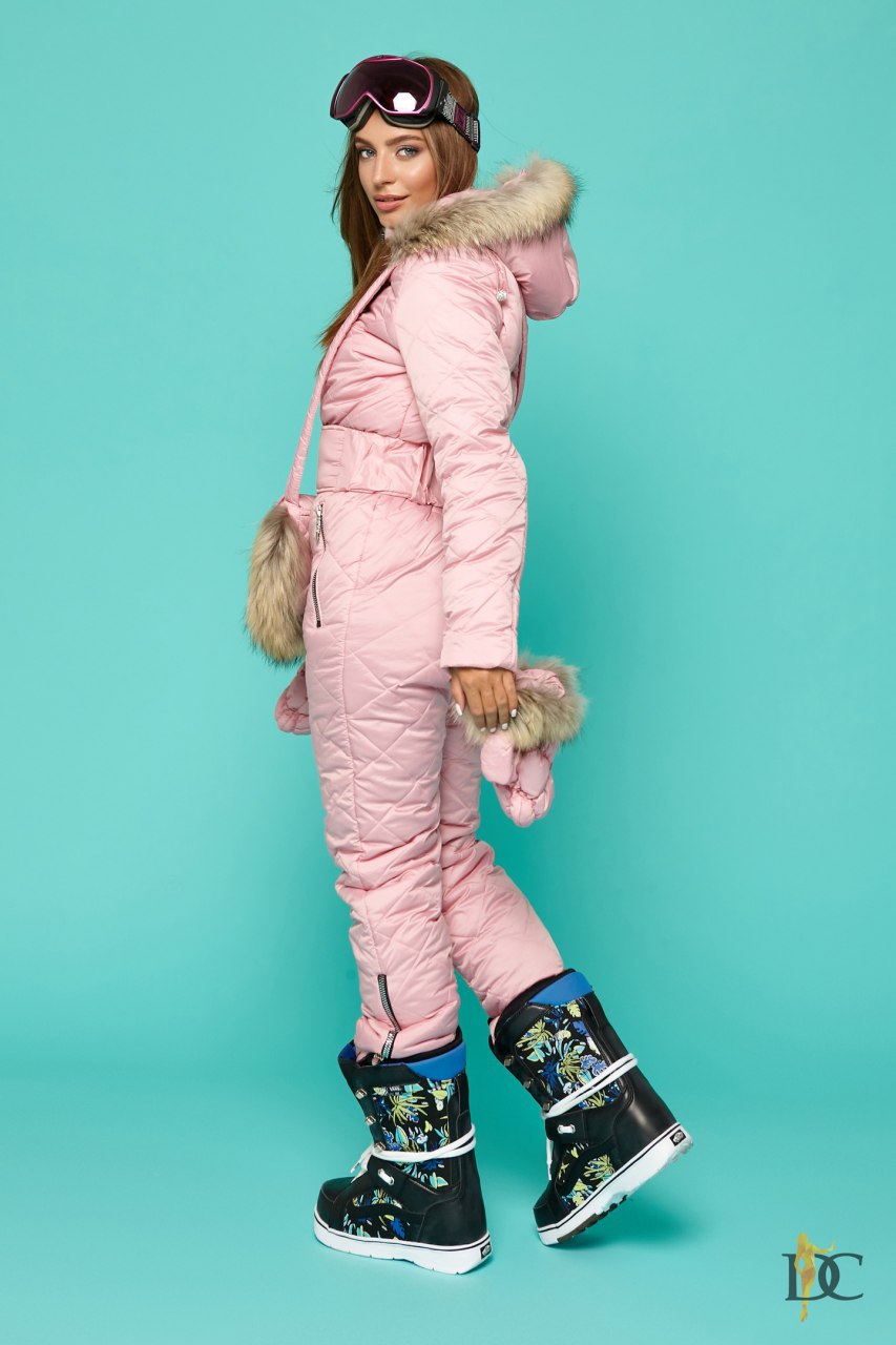 Person wearing a pink snowsuit with fur trim on a teal background