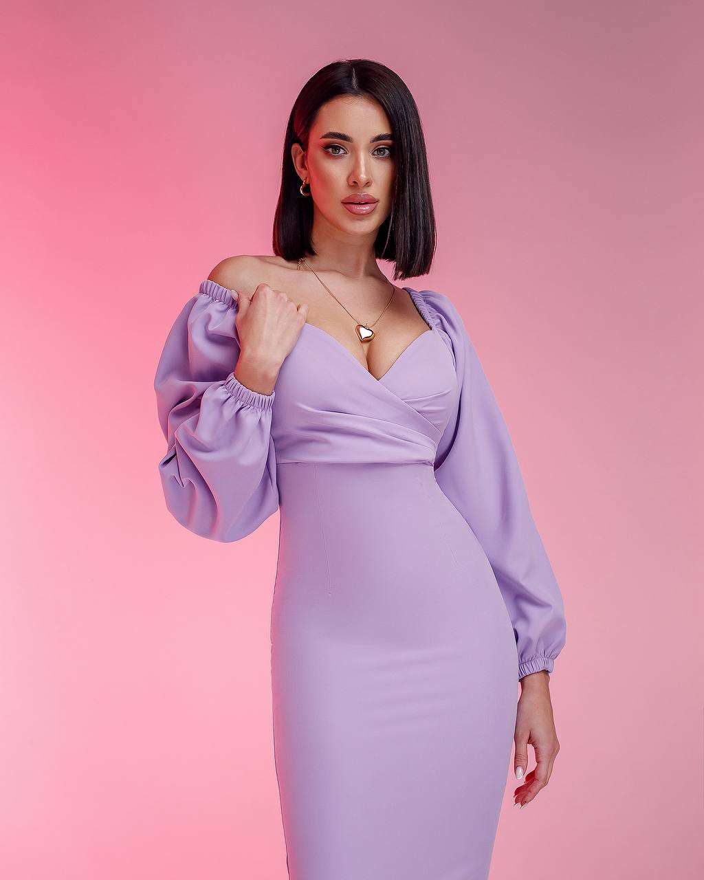 Woman wearing a lavender dress with balloon sleeves against a pink background