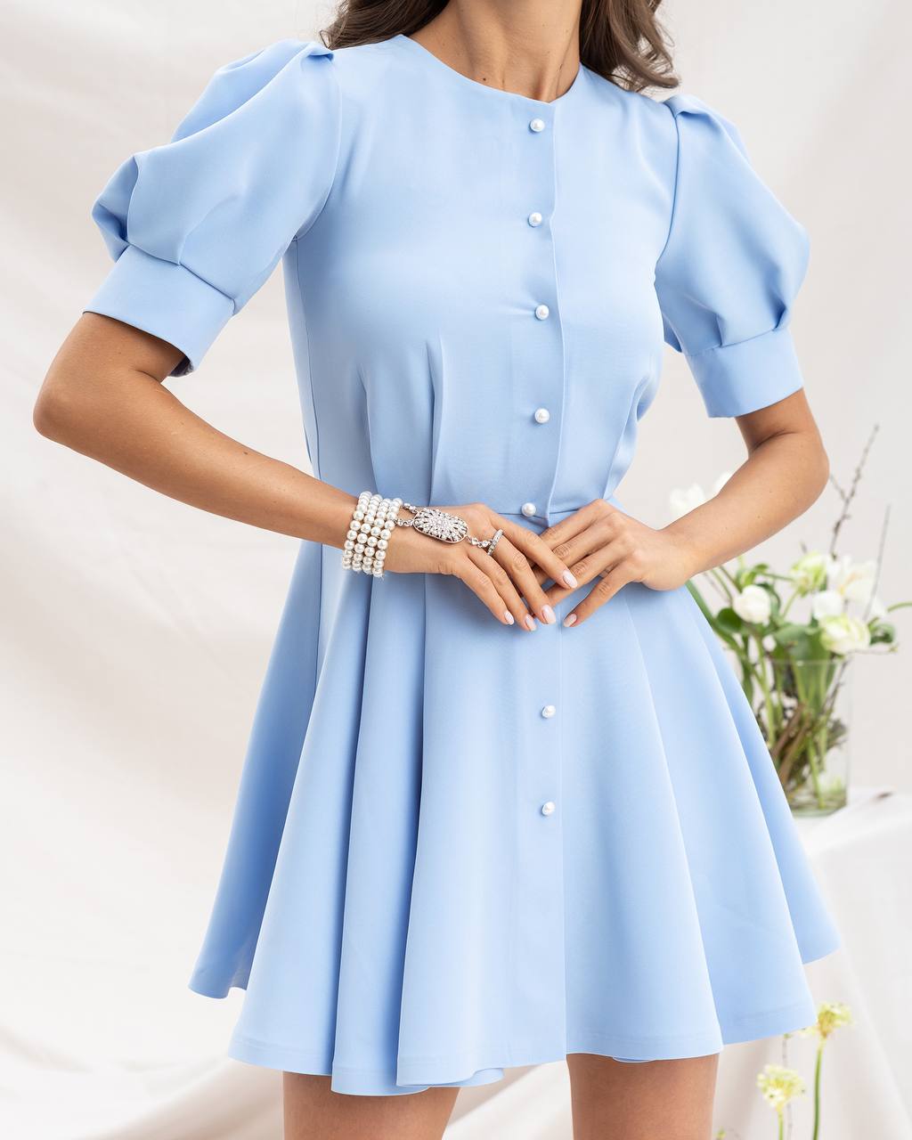Light blue dress with short sleeves and buttons on a neutral background