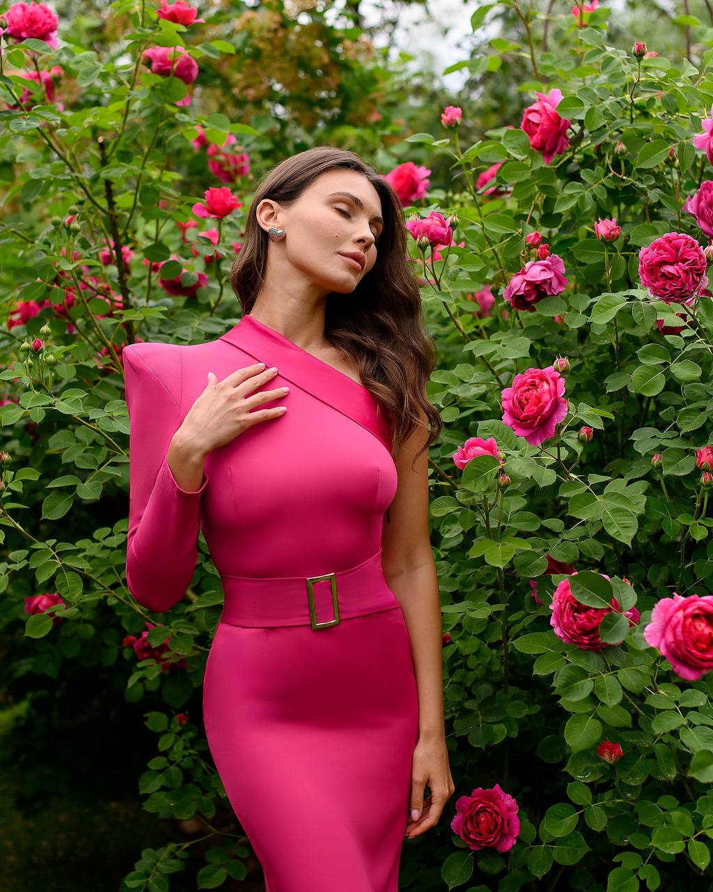 Woman in a pink dress standing among pink flowers