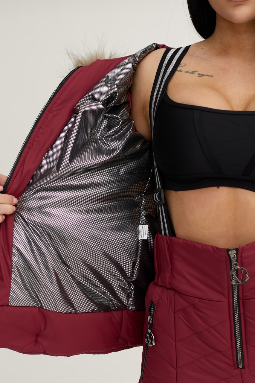 Person wearing a red puffer jacket with a black interior lining, on a plain background.