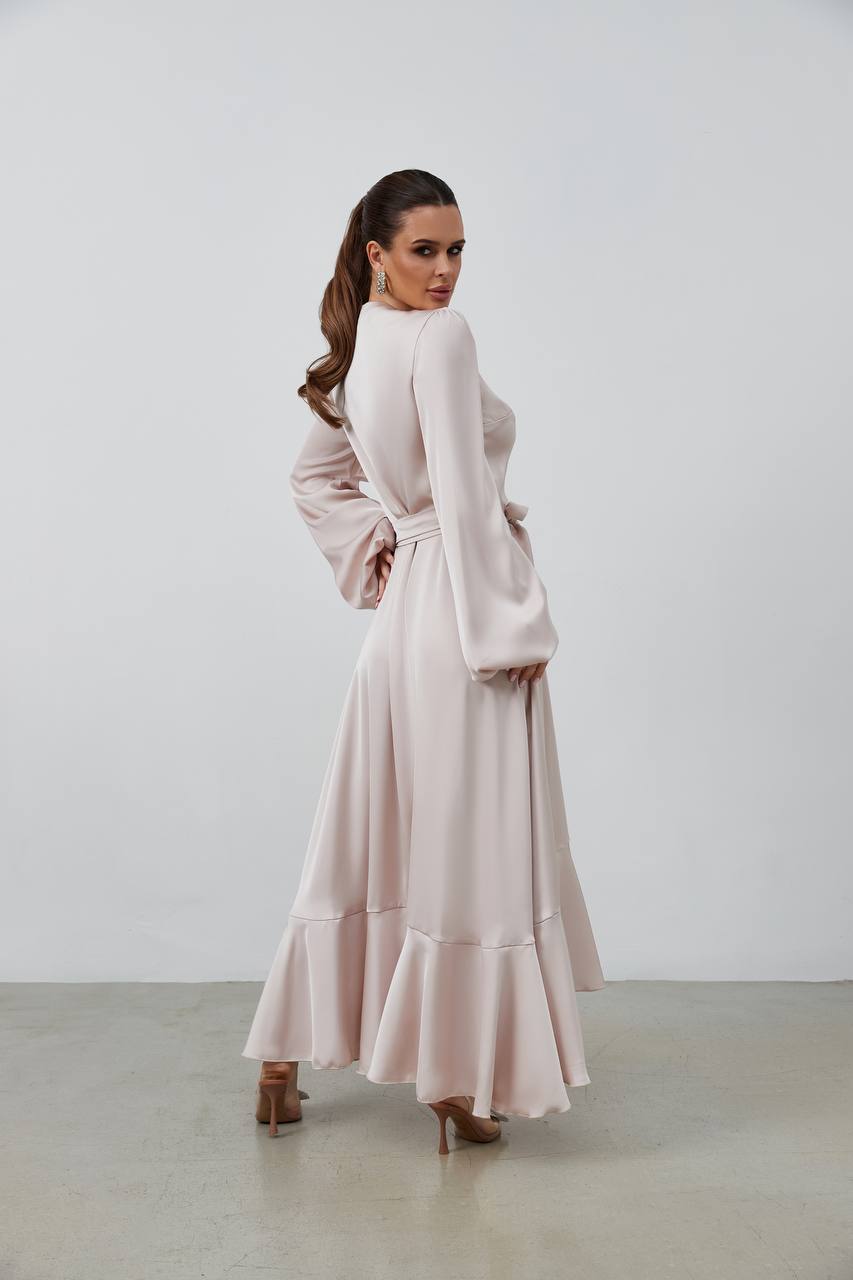 Woman wearing a long, light-colored dress against a plain background