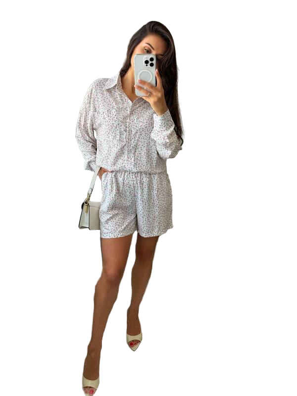 Woman taking a mirror selfie wearing a white patterned outfit on a white background