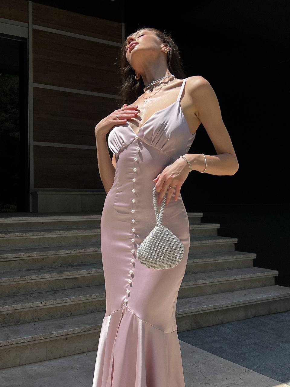 Woman in a pink dress holding a handbag on steps