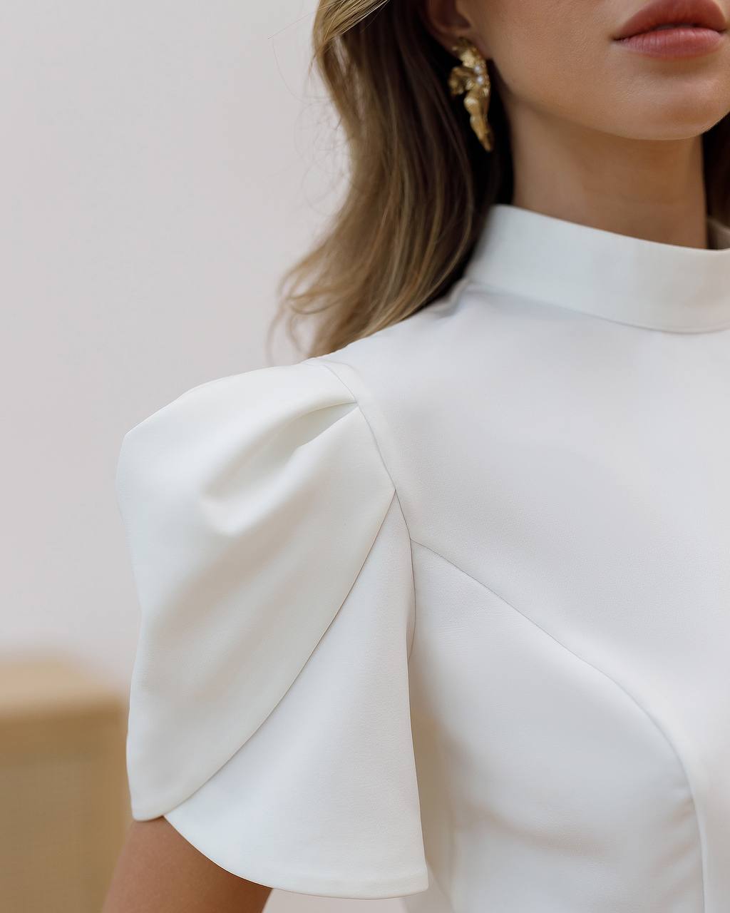 White dress with ruffled sleeves worn by a person, blurred background