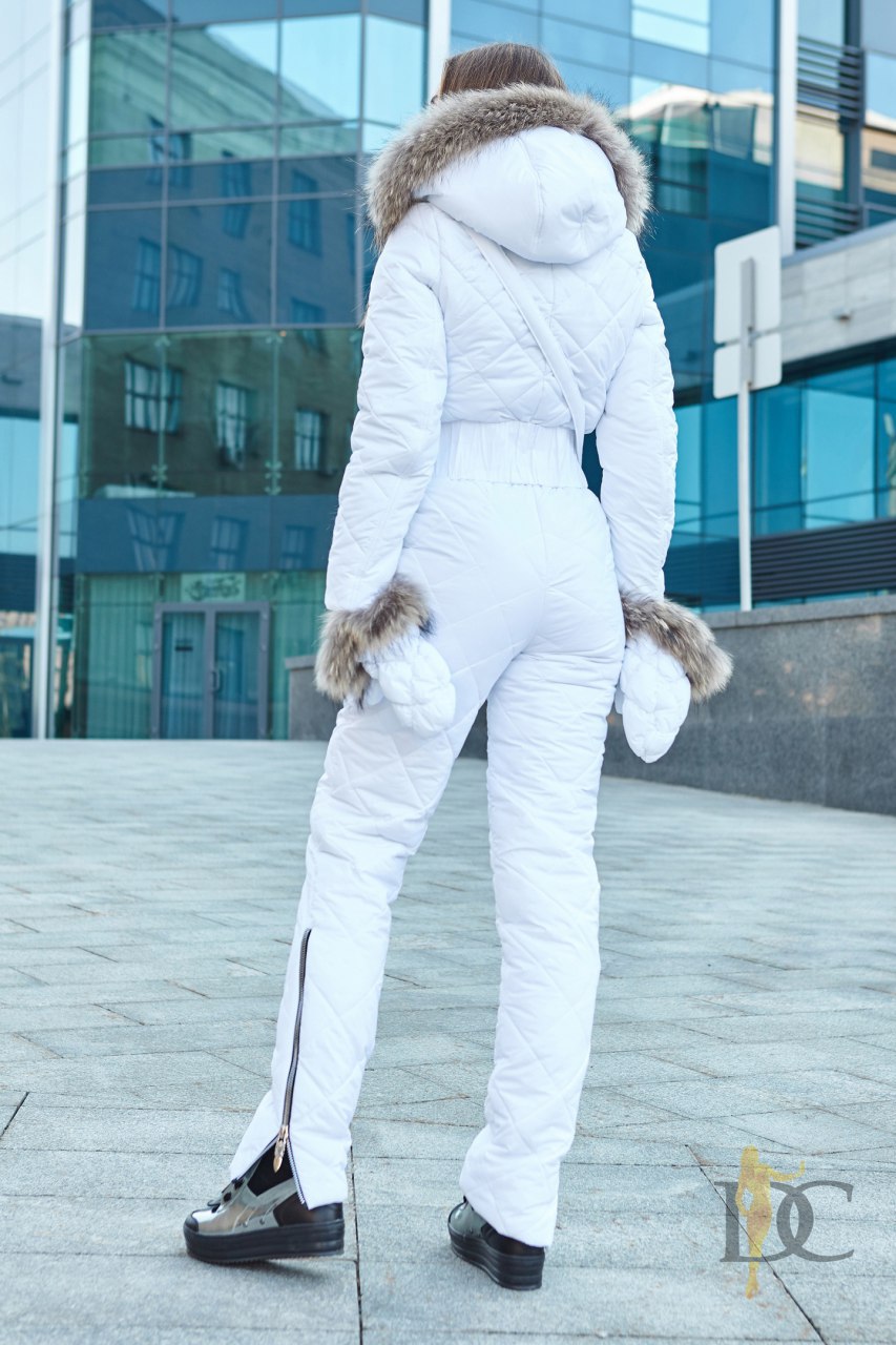 Person wearing a white winter outfit with fur-lined hood and cuffs in an urban setting.