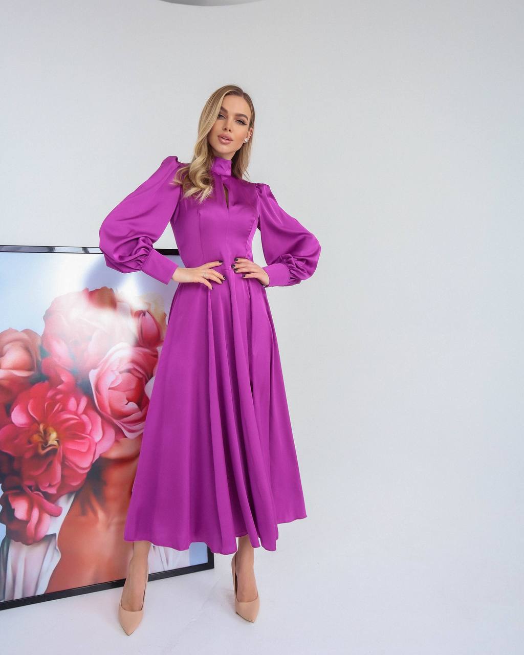 Woman wearing a purple dress standing in front of a floral painting