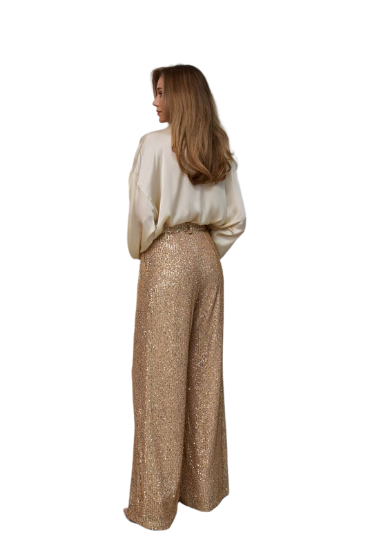 Woman wearing a white top and gold pants on a white background