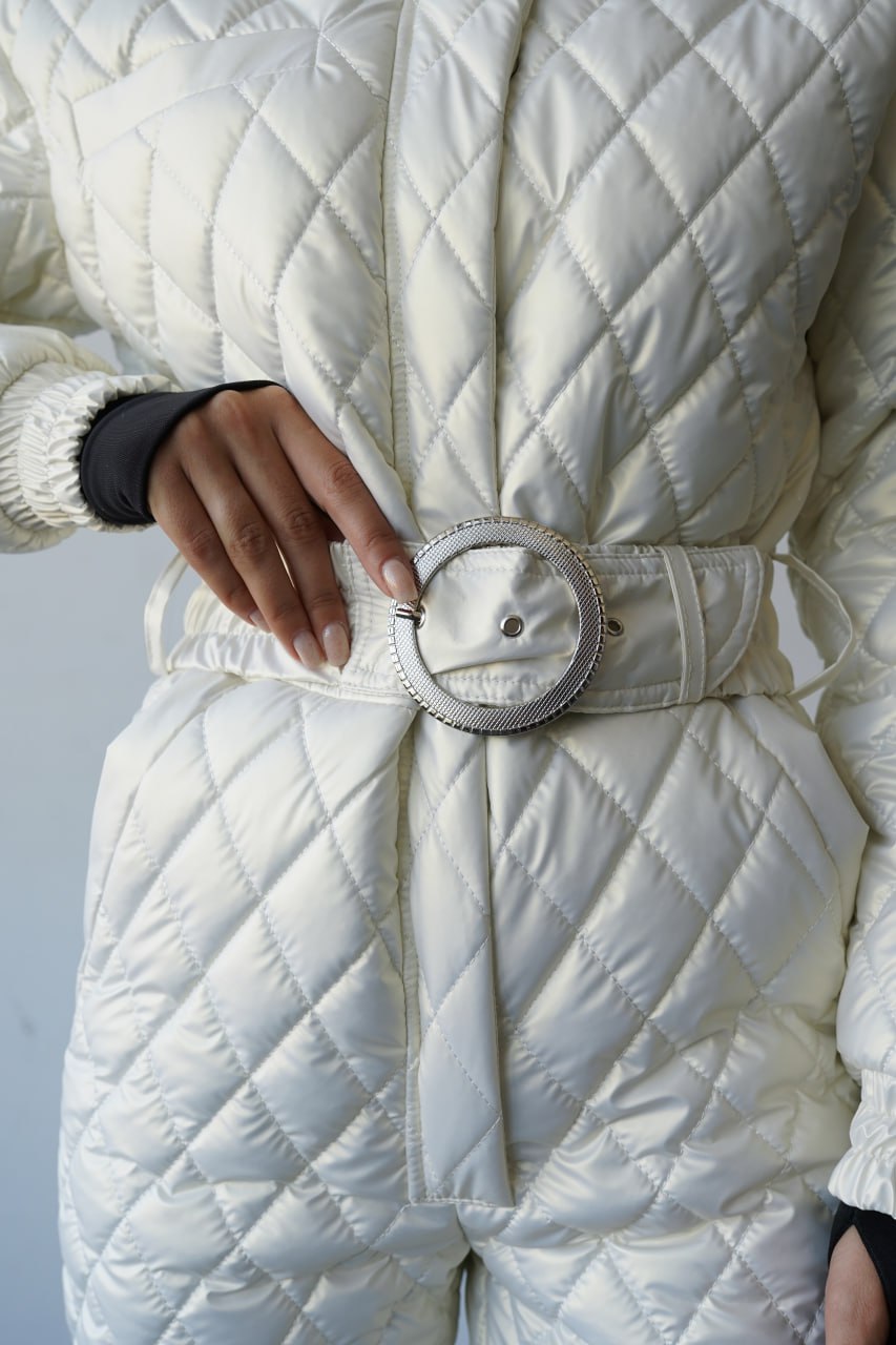 White quilted jacket with a belt on a neutral background