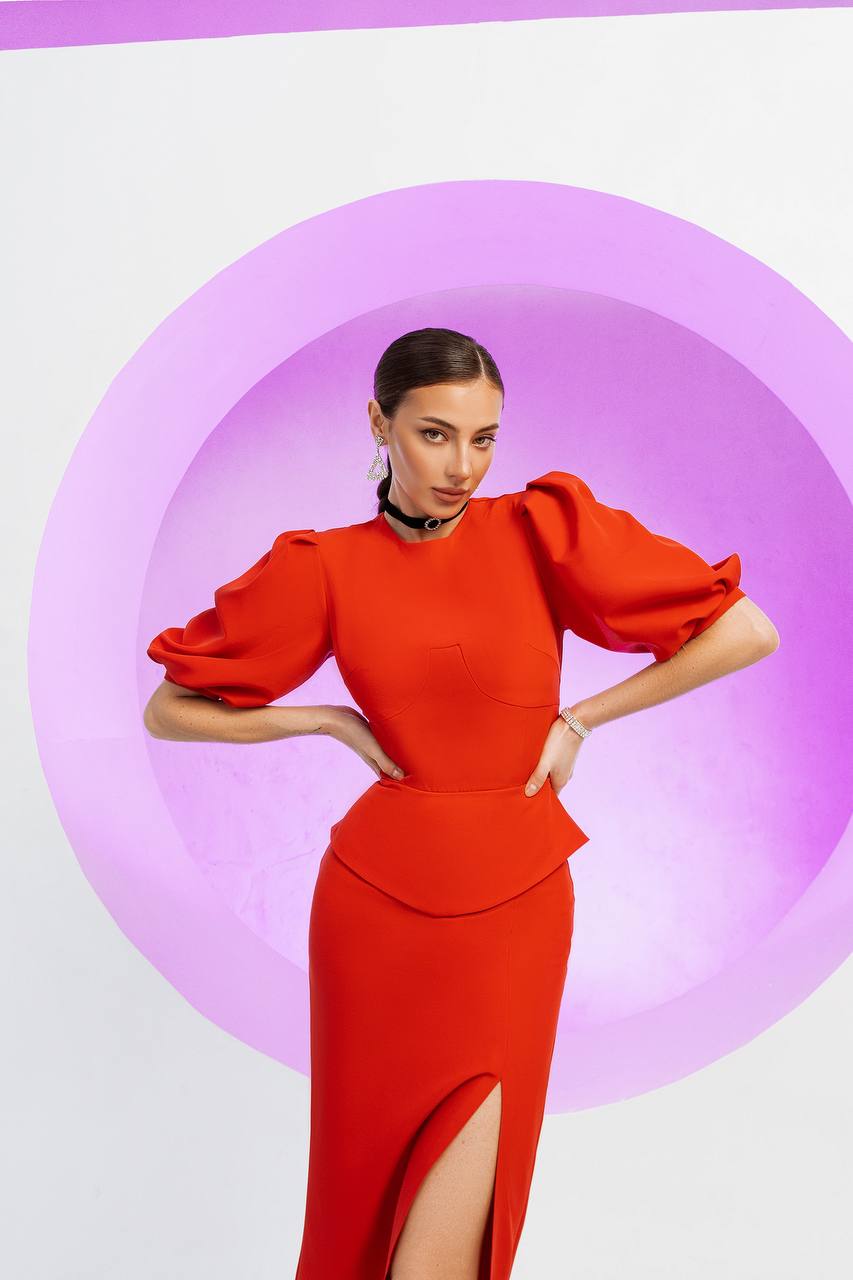 Woman wearing a red dress with puffed sleeves against a pink and white background
