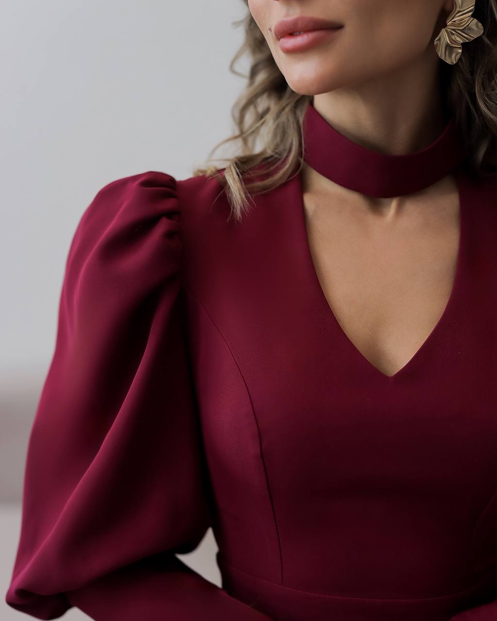 Close-up of a burgundy dress with a V-neck and puffed sleeves.