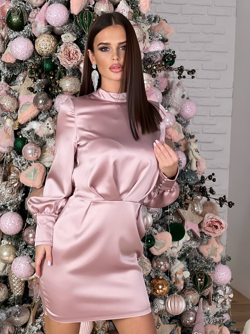 Woman in a pink dress standing in front of a decorated Christmas tree.
