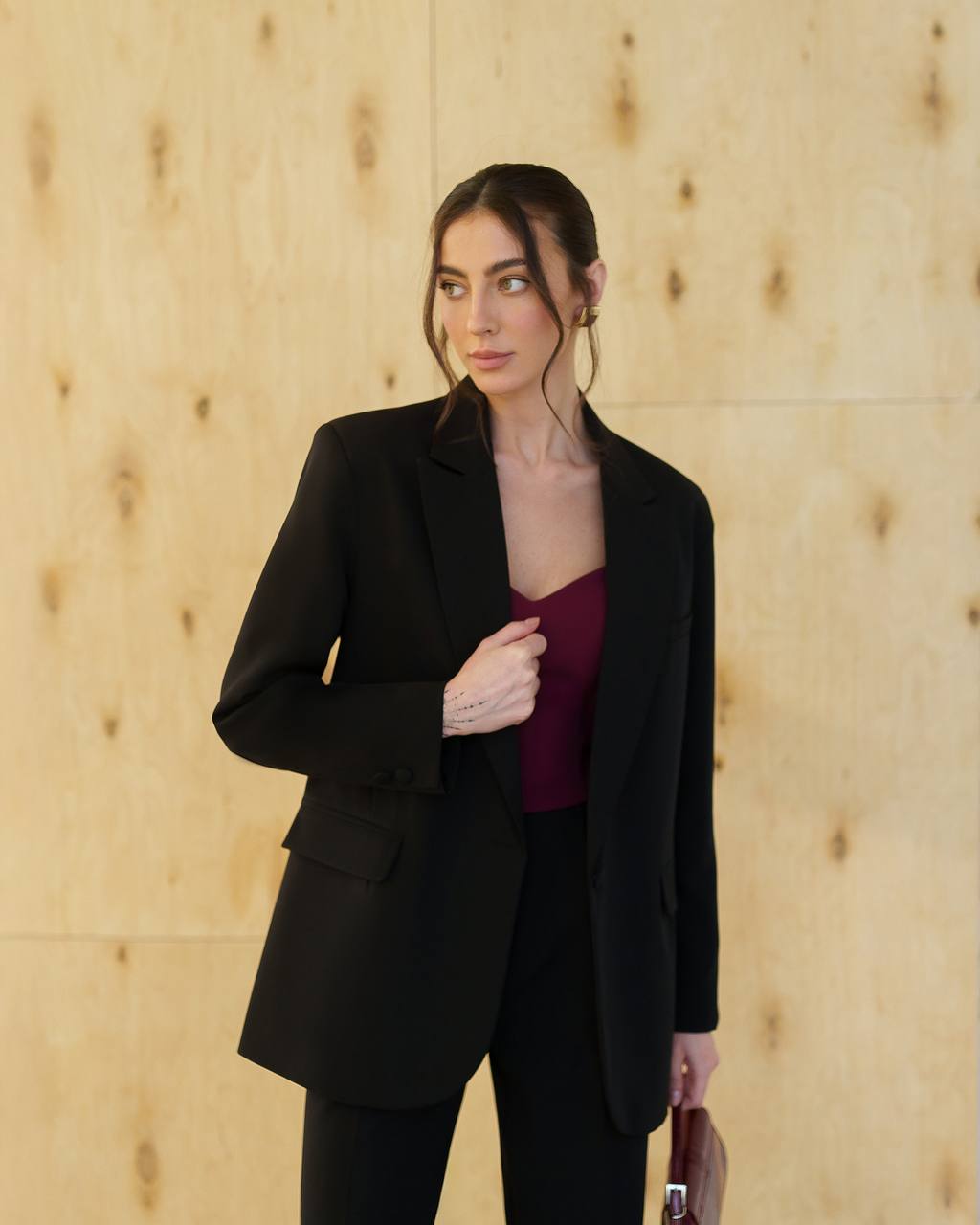 Woman wearing a black suit against a wooden paneled wall