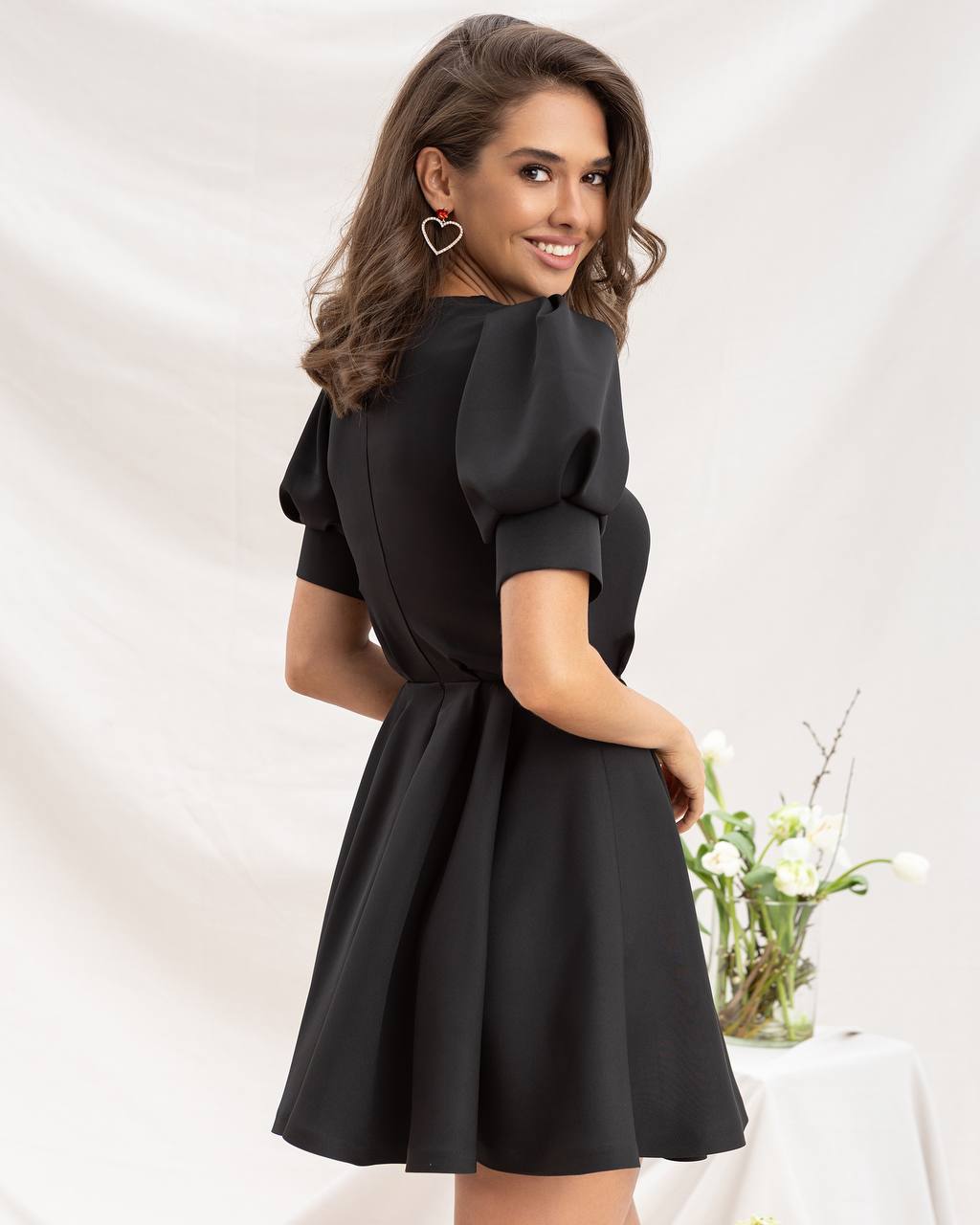 Woman wearing a black dress with puffed sleeves against a white background