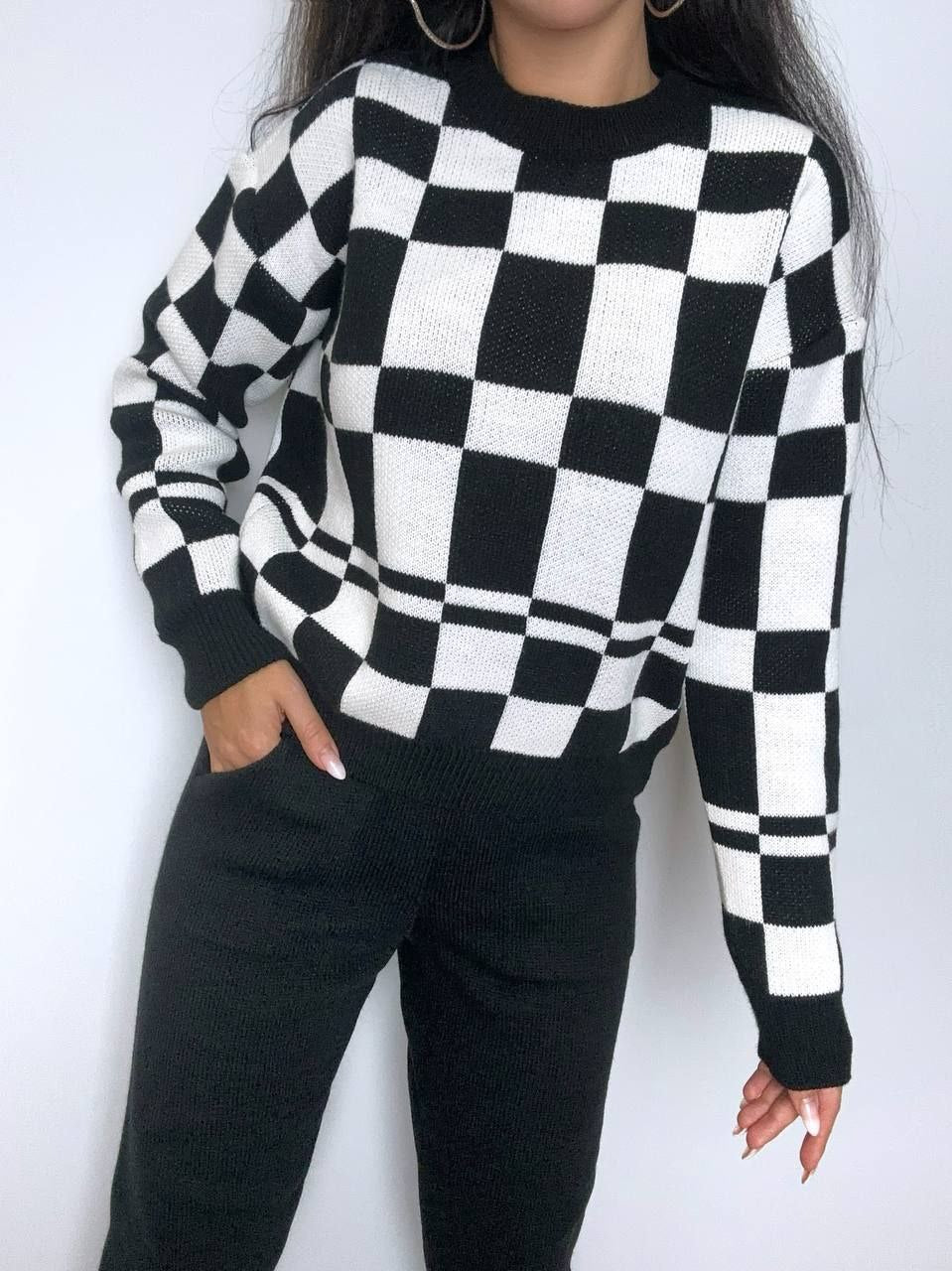 Person wearing a black and white checkered sweater against a white background