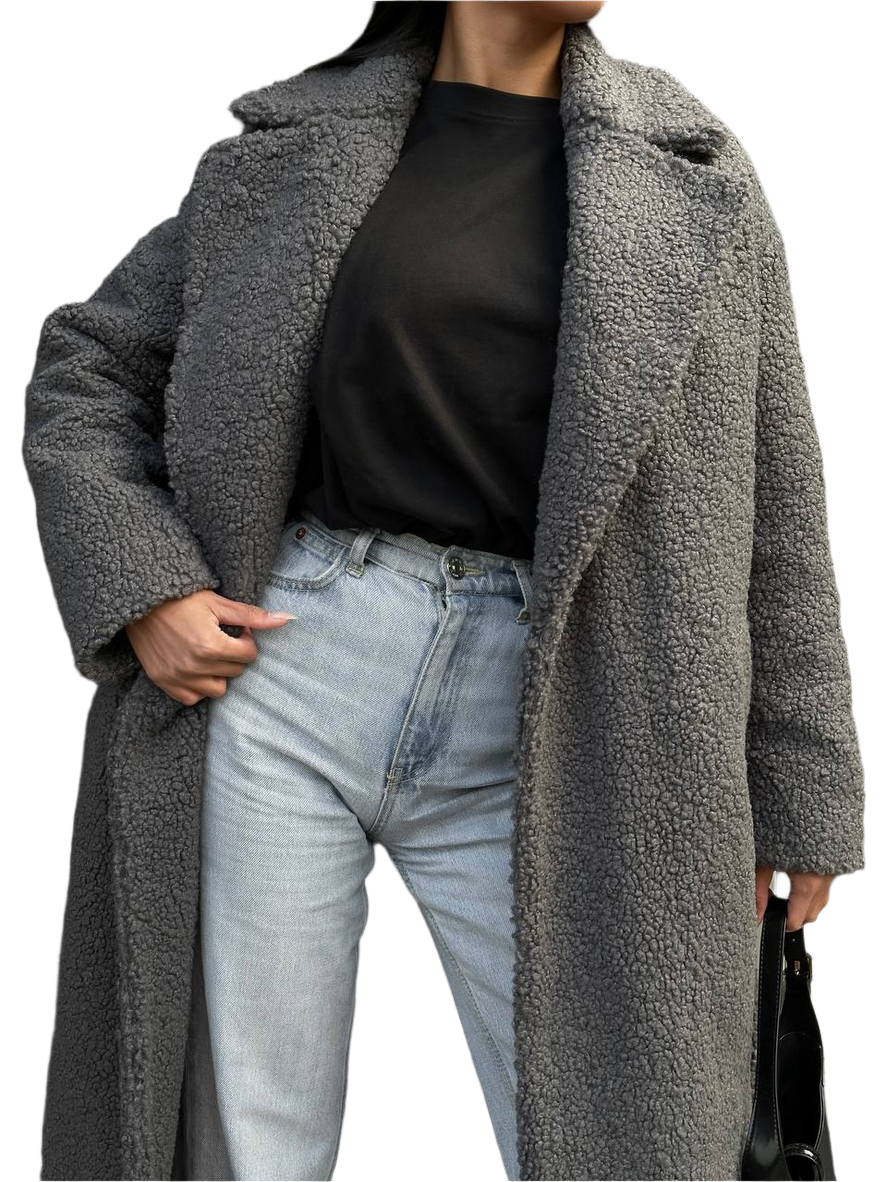 Person wearing a long gray teddy coat over a black top and light blue jeans on a white background