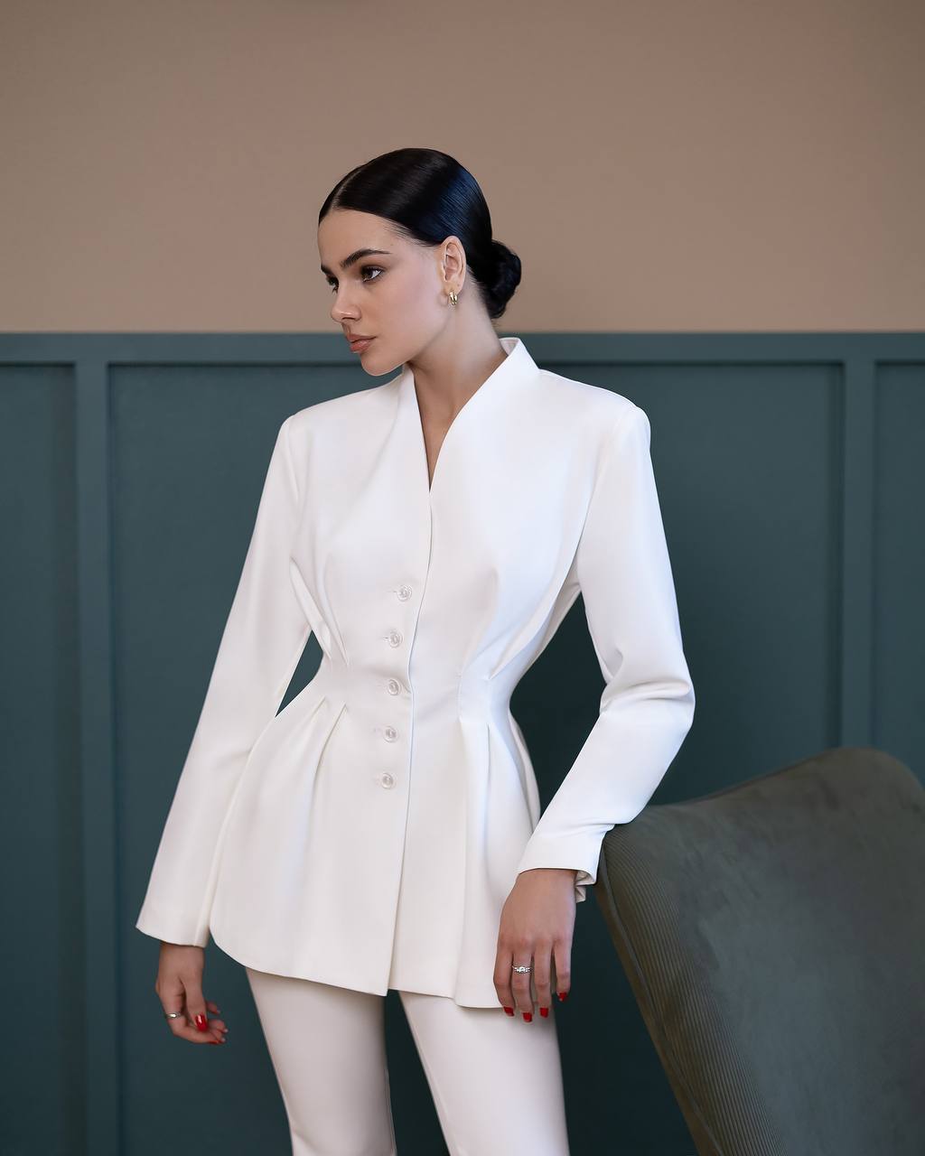 Woman wearing a white suit standing against a neutral background