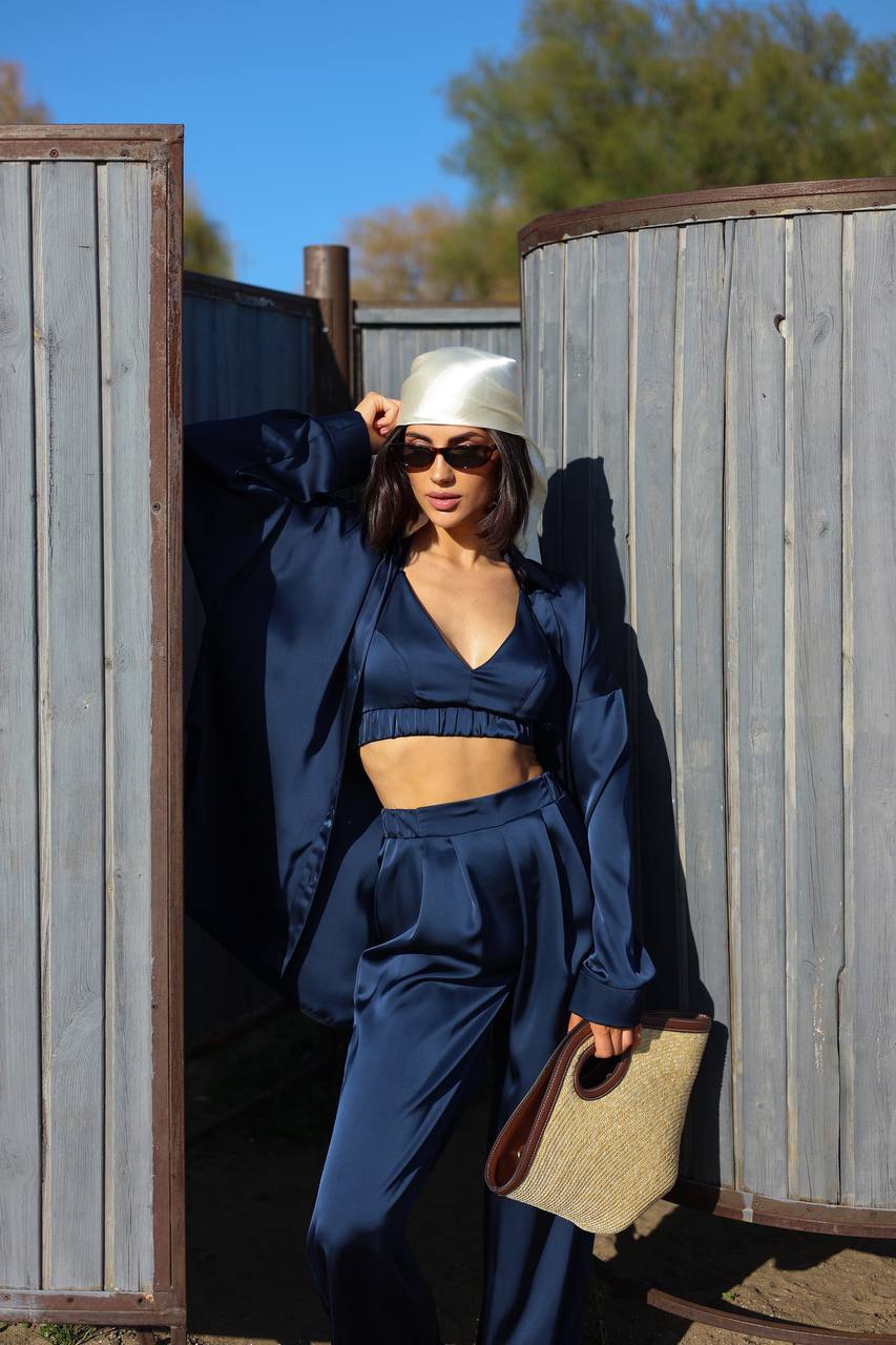 Woman in a blue outfit standing against a wooden fence