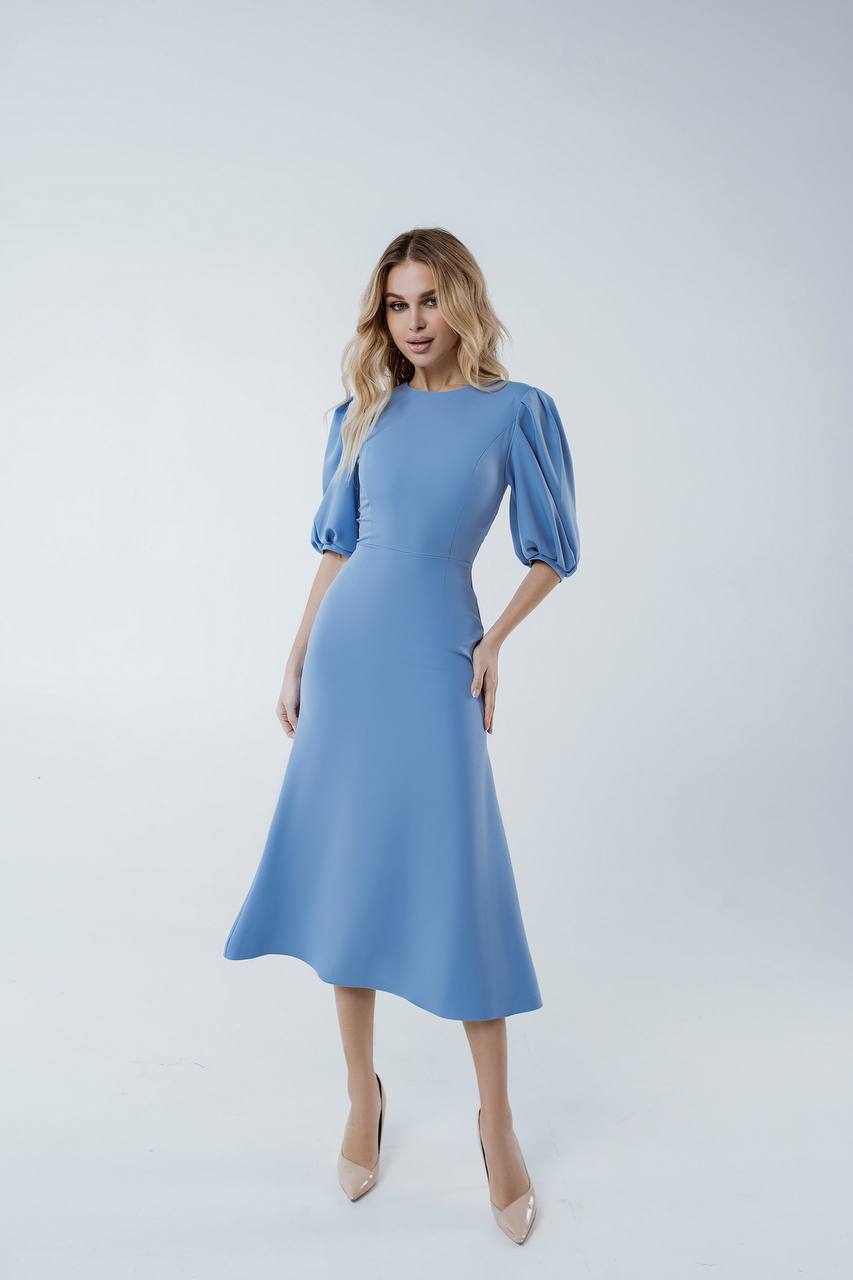 Woman wearing a light blue dress with puff sleeves on a white background