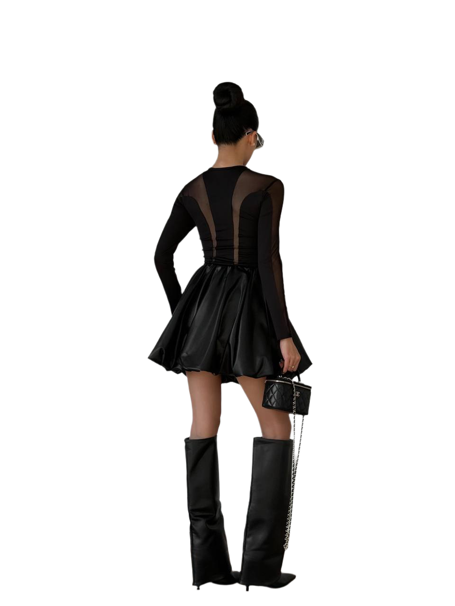 Person wearing a black dress with sheer panels and black knee-high boots on a white background