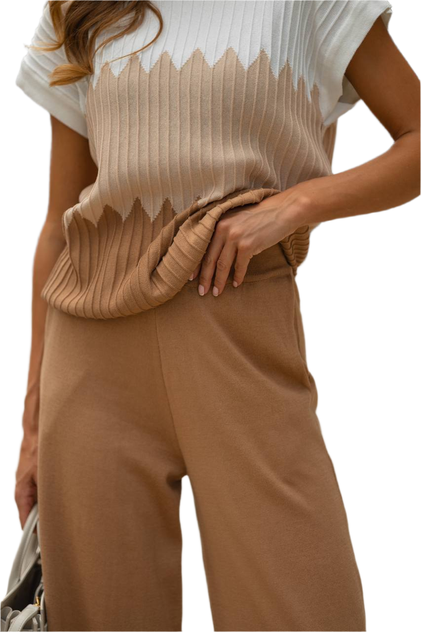Person wearing a beige ribbed top and brown pants on a white background