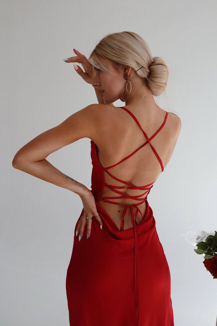 Woman wearing a red dress with a strappy back design, standing against a plain background.