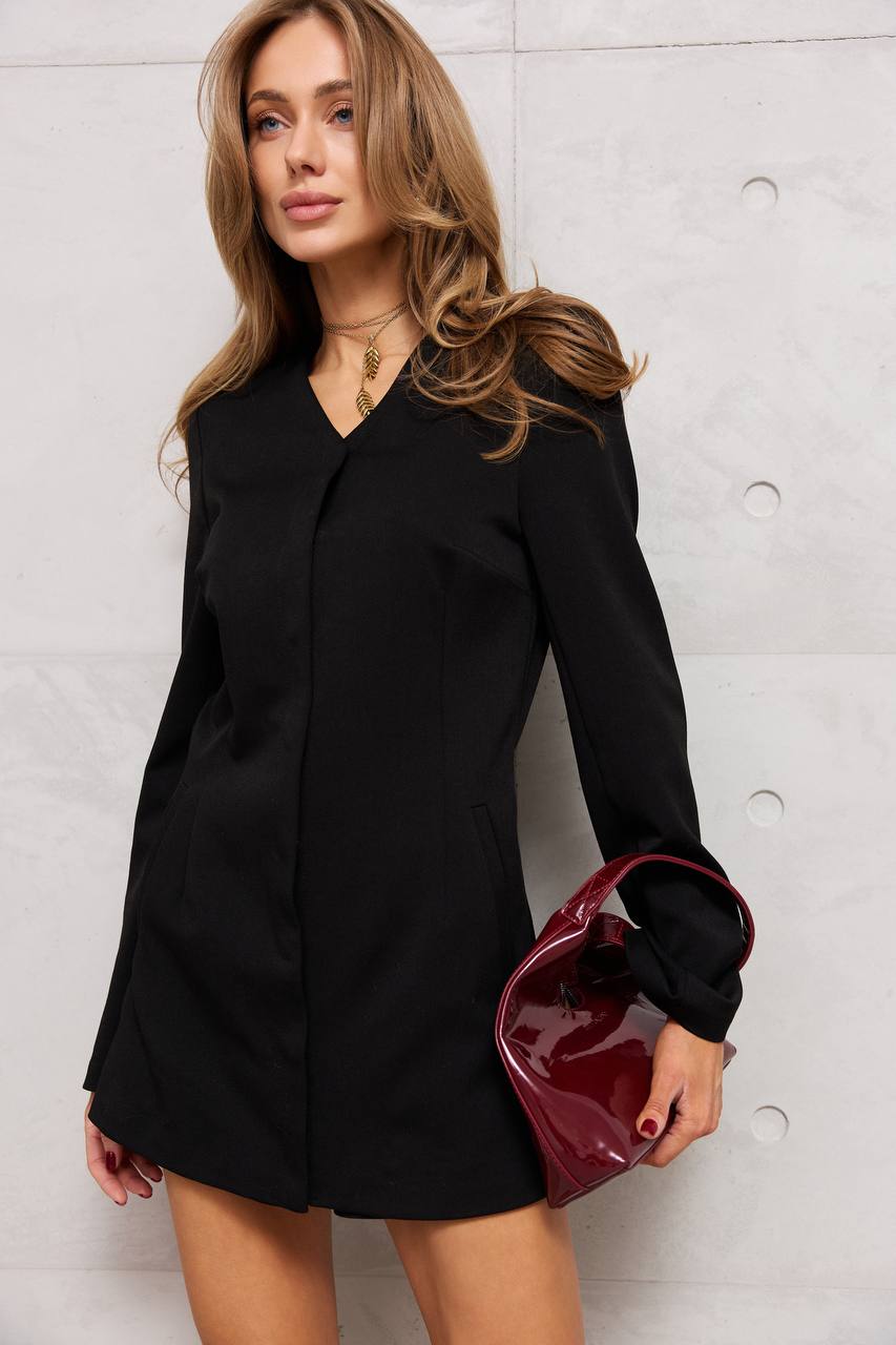 Woman wearing a black dress holding a red handbag against a light background