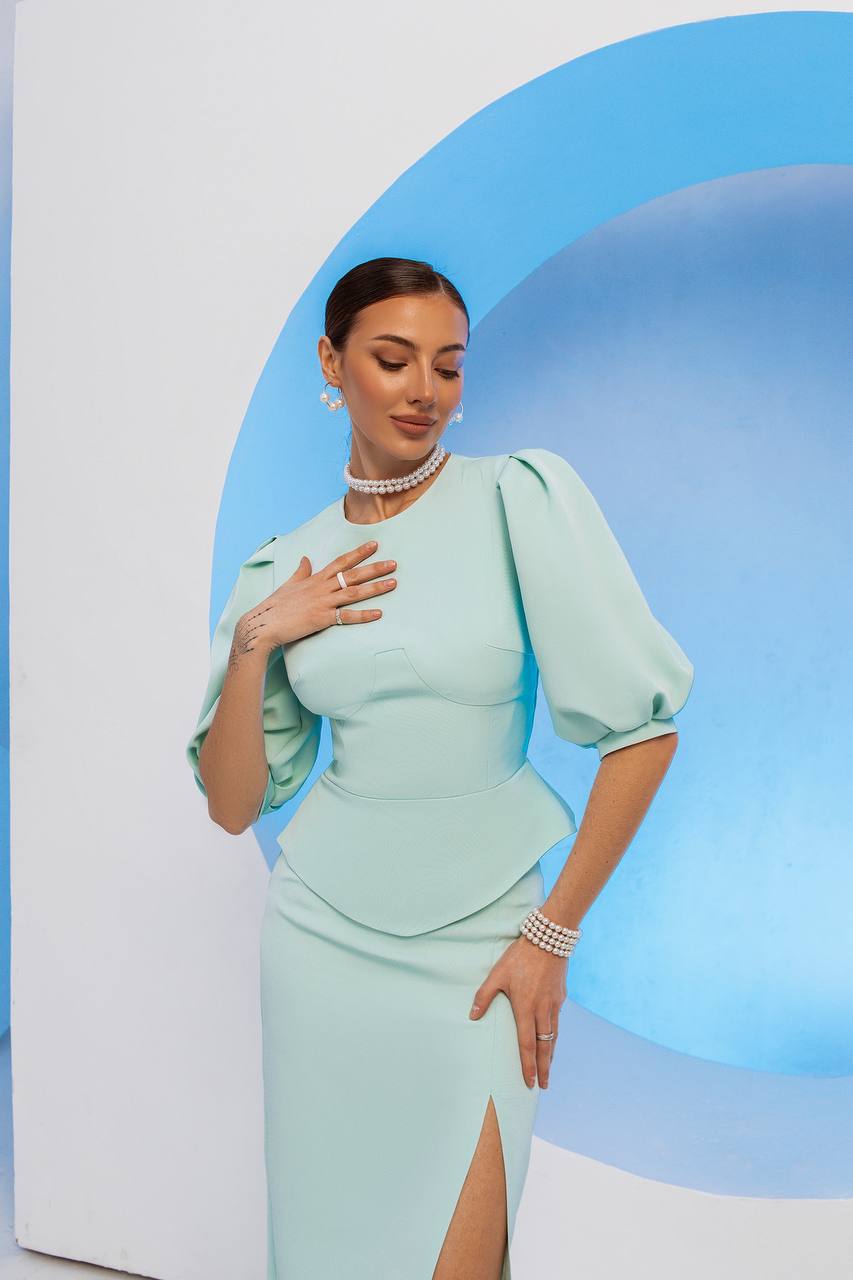 Woman in a light blue dress with puffed sleeves against a blue and white background