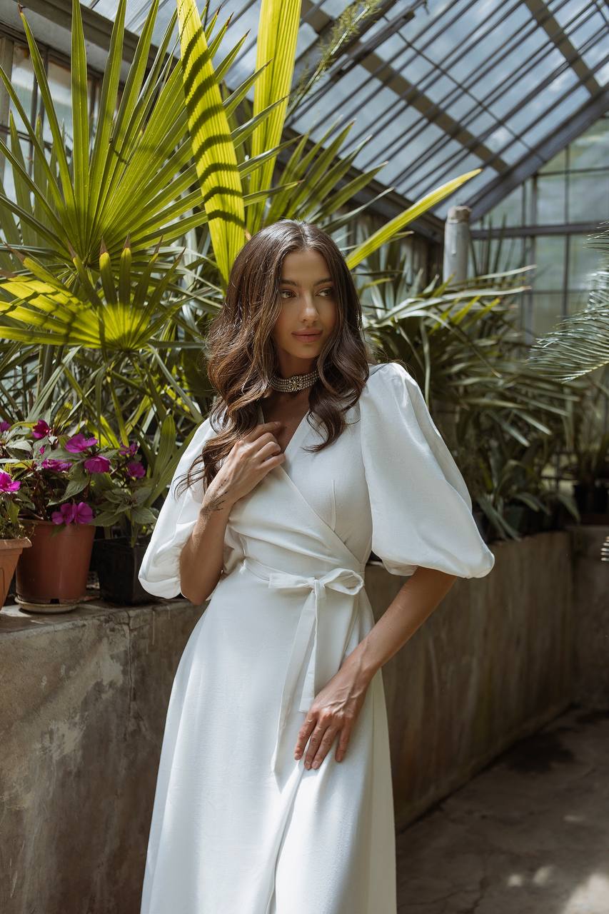 Woman in a white dress standing in a greenhouse with plants around