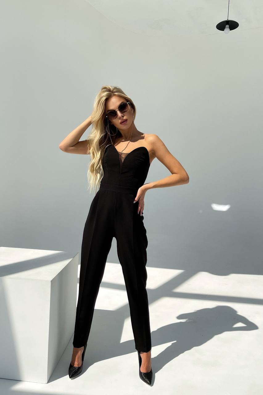 Woman wearing a black jumpsuit against a white background