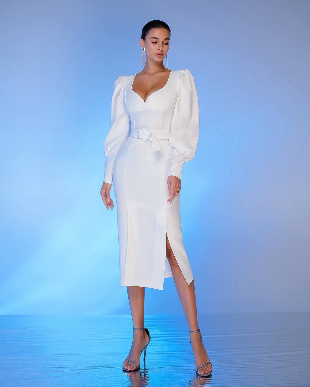 Woman wearing a white dress with puffed sleeves on a blue gradient background