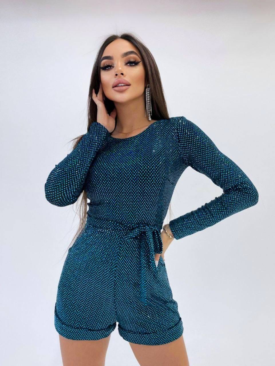 Woman wearing a teal sequin outfit against a white background