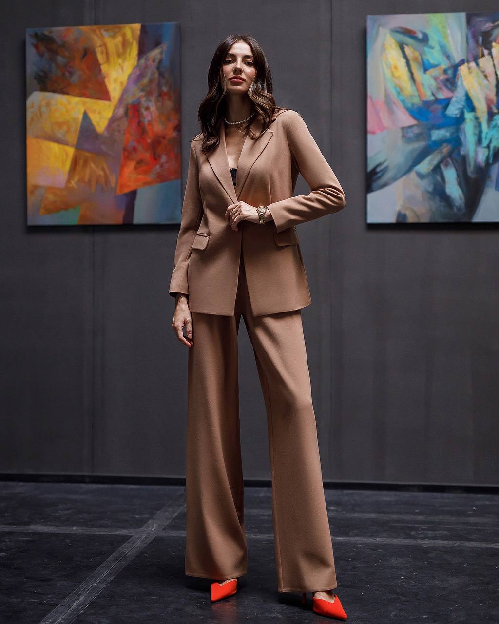 Woman in a beige suit standing in front of abstract paintings