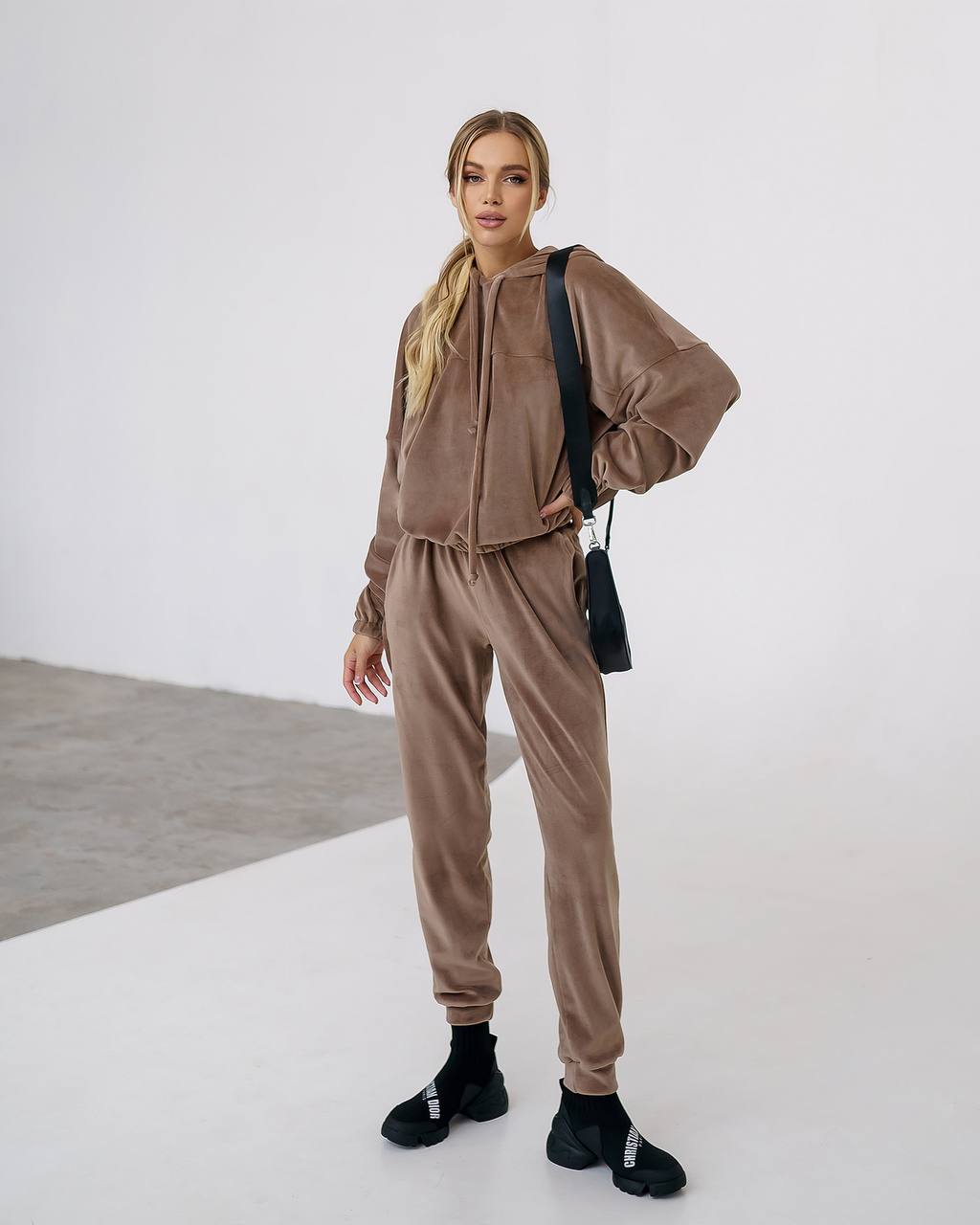 Woman wearing a brown tracksuit with black shoes on a white background