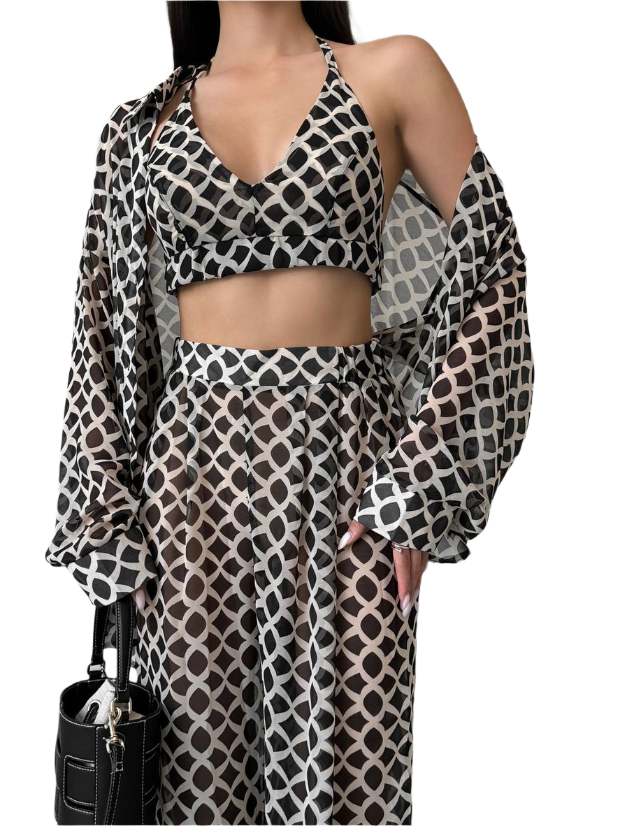Woman wearing a patterned outfit with a black handbag on a white background