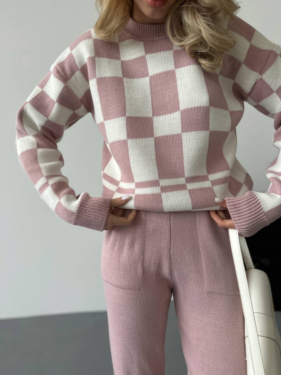 Person wearing a pink and white checkered sweater and matching pants.