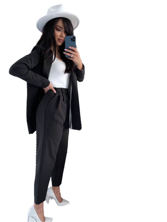 Woman in a black outfit with a white hat taking a selfie on a white background