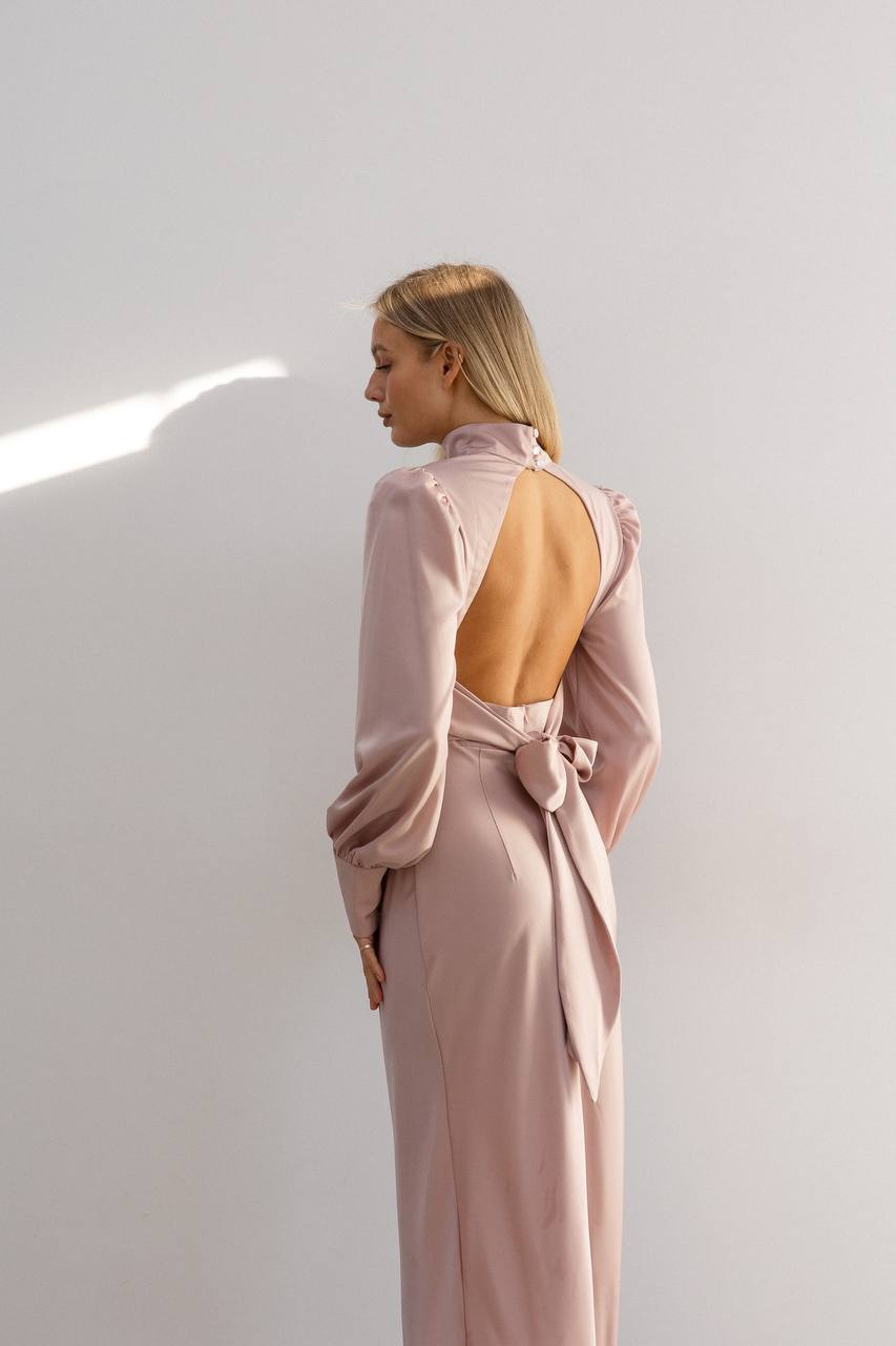 Woman wearing a pink dress with a cut-out back against a white background