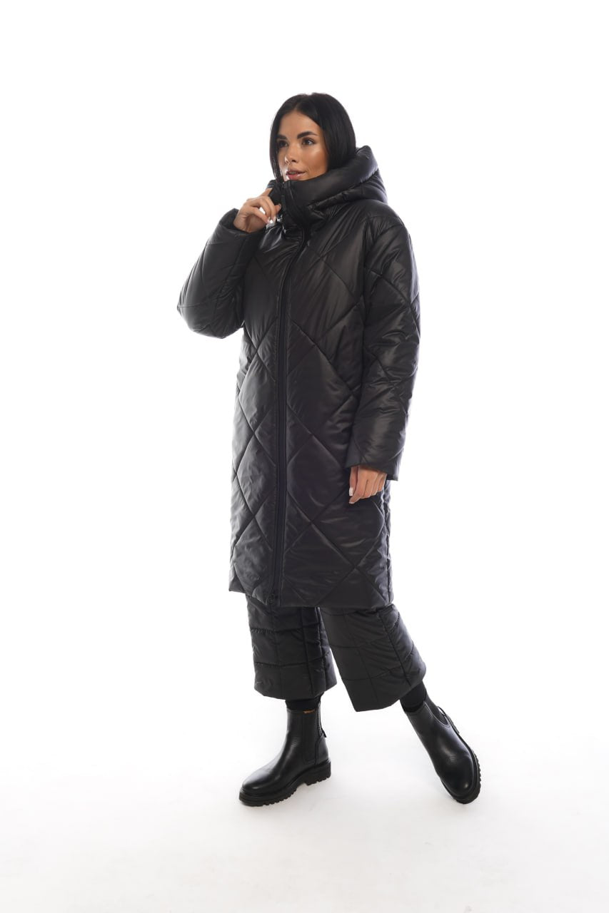 Person wearing a long black quilted coat on a white background