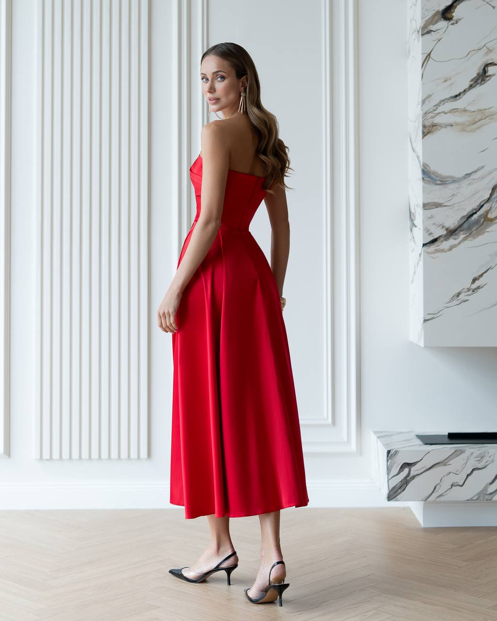 Woman in a red dress standing in a stylish interior setting