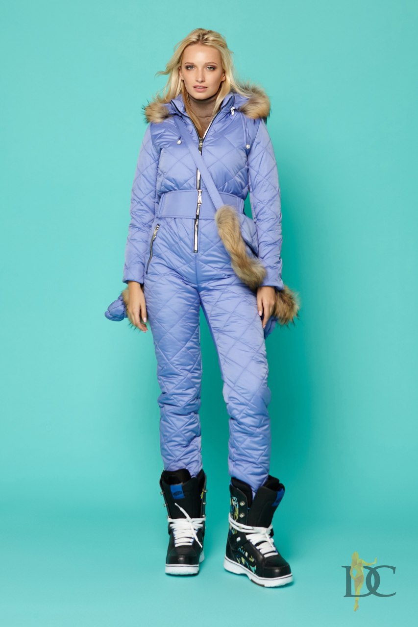 Woman wearing a blue winter outfit with fur accents on a teal background